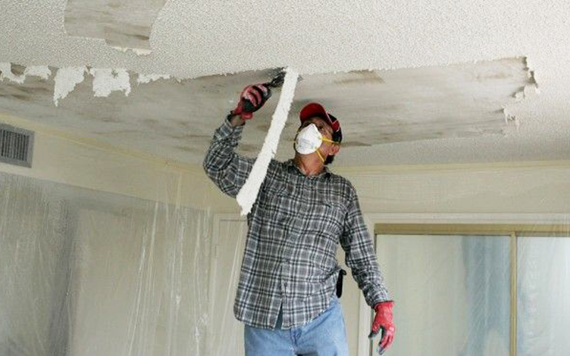 Worker scraping a textured ceiling