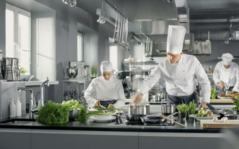 Chef and cooks working in a kitchen full of stainless steel